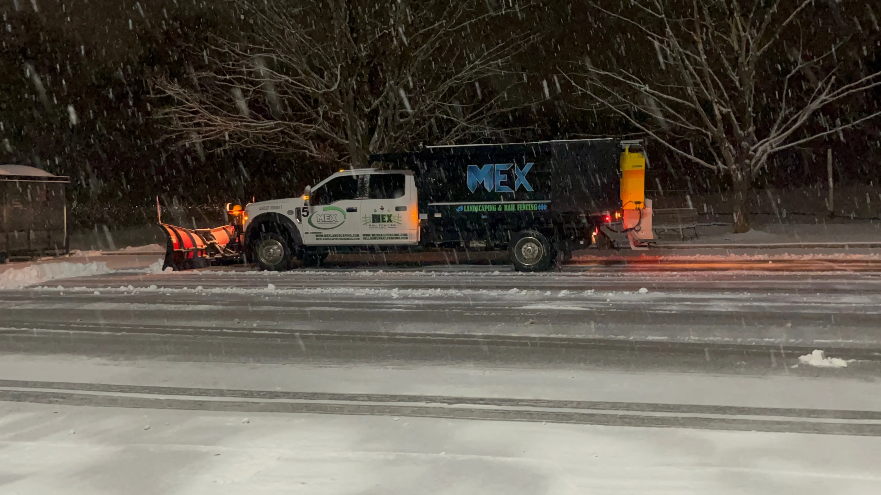 MEX snowplow truck clearing pavement during a nighttime snowfall
