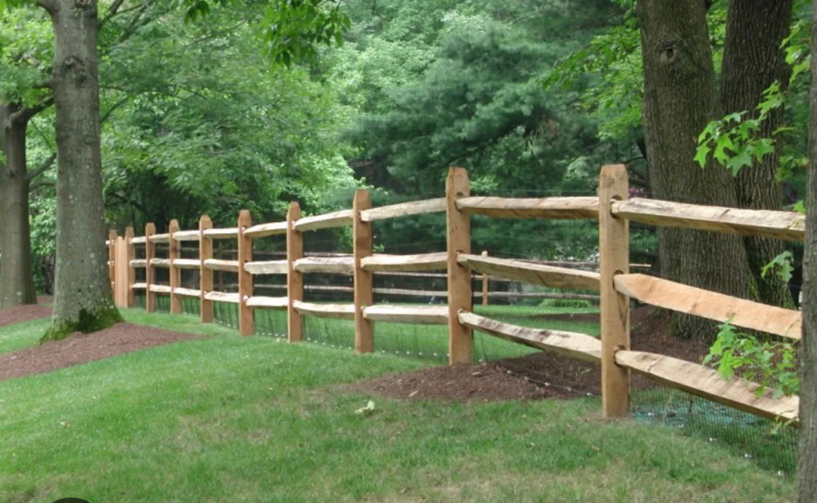 Long split rail fence line running through a wooded property