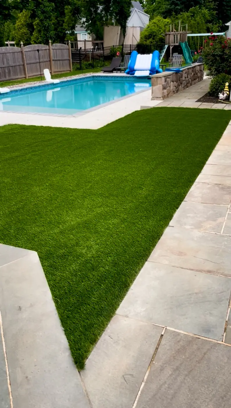 Turf lawn meeting bluestone paving beside a pool